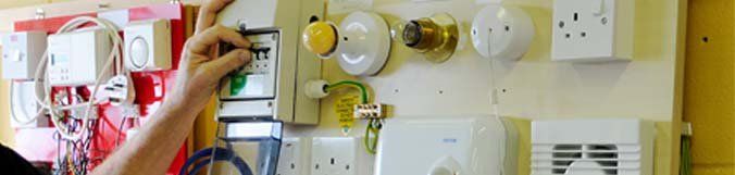 A person is working on a wall with electrical equipment.